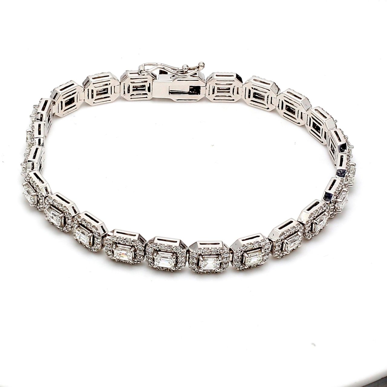 7' Halo tennis bracelet with prong set rounds around emerald cut diamond center stones.  D6.84ct.t.w.